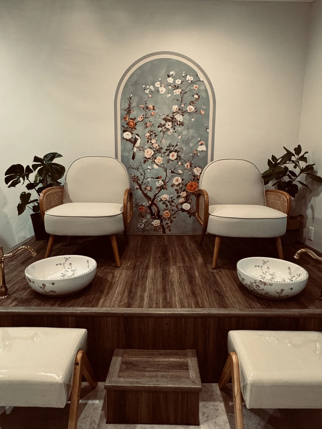 Botanical wall, cream chairs and rich wood in the Ase’moon pedicure room